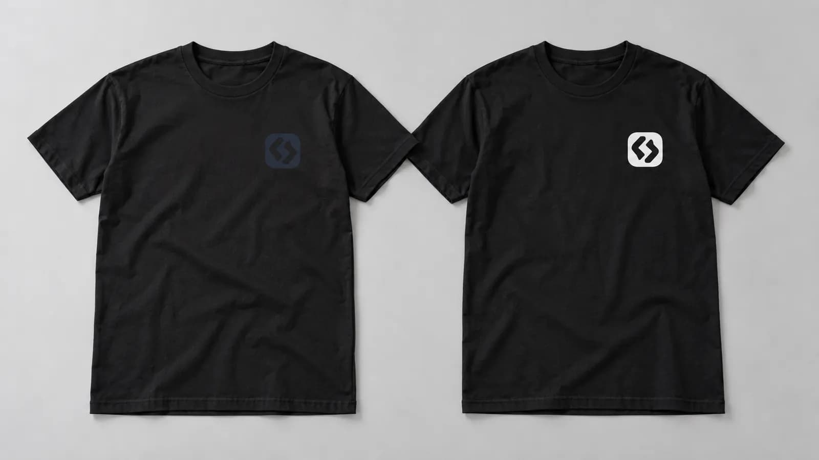 Zwei schwarze T-Shirts: eines mit dunklem, kaum sichtbarem Logo, eines mit hellem, gut lesbarem Logo