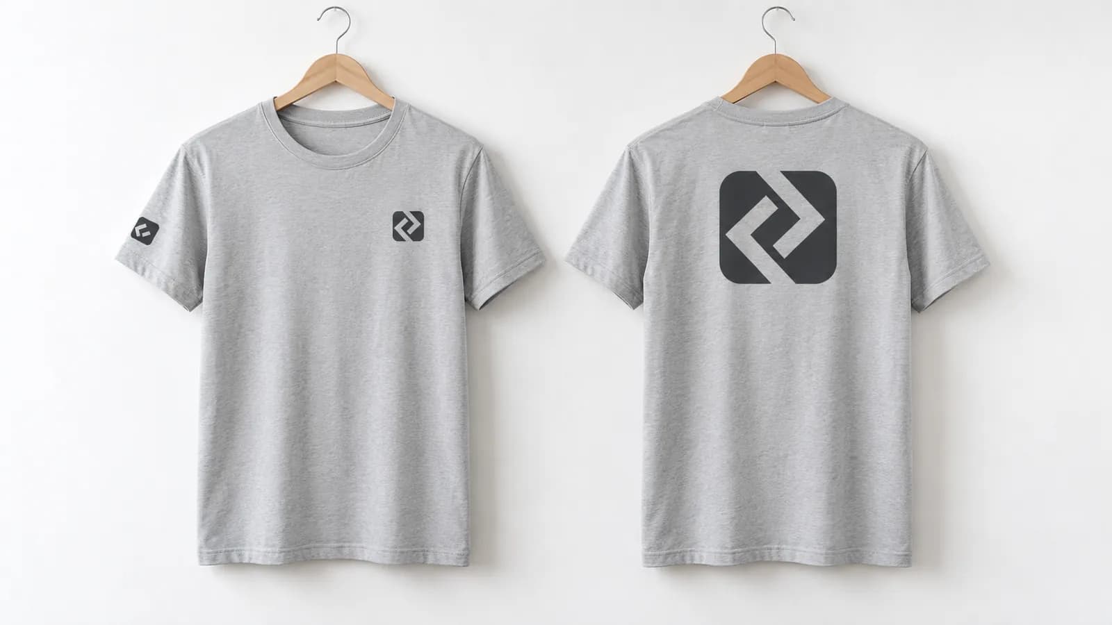 Graue T-Shirts auf Bügeln: vorne Brustlogo und Ärmelzeichen, hinten großer Rückendruck